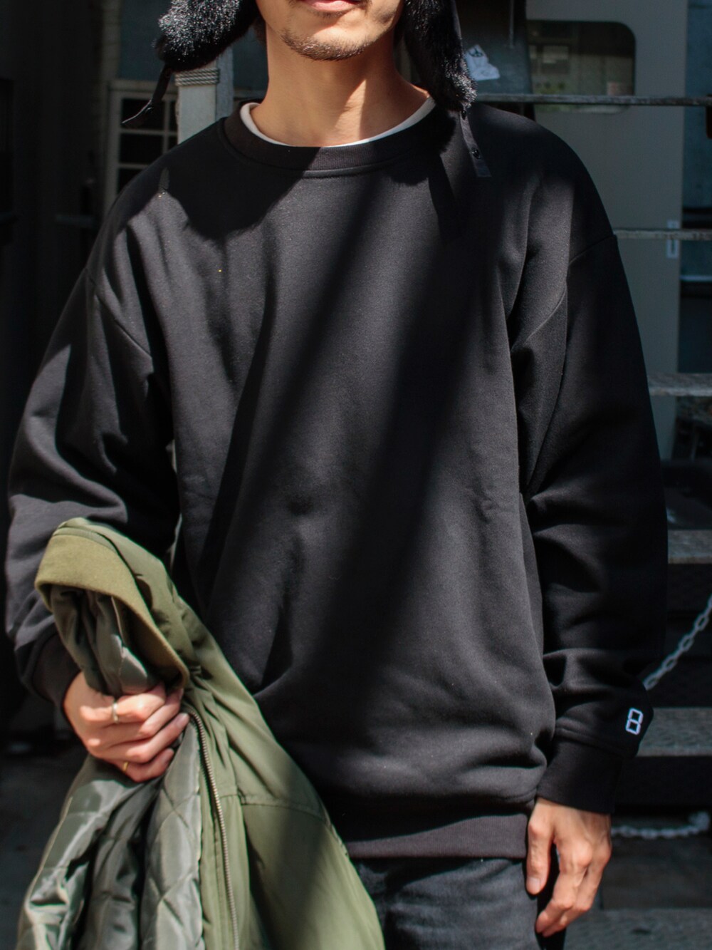 ブラック系のスウェット、グリーン系のブルゾン、ブラック系のスニーカーを着用したメンズの秋コーディネートの2枚目の写真