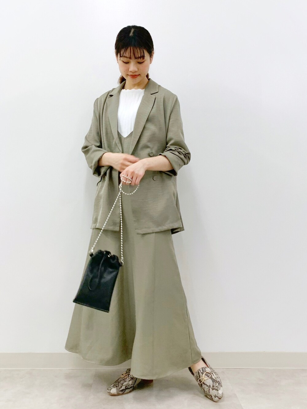 グリーン系のテーラードジャケット、グリーン系のワンピース、ホワイト系のニット/セーターを着用したレディースの春コーディネートの2枚目の写真