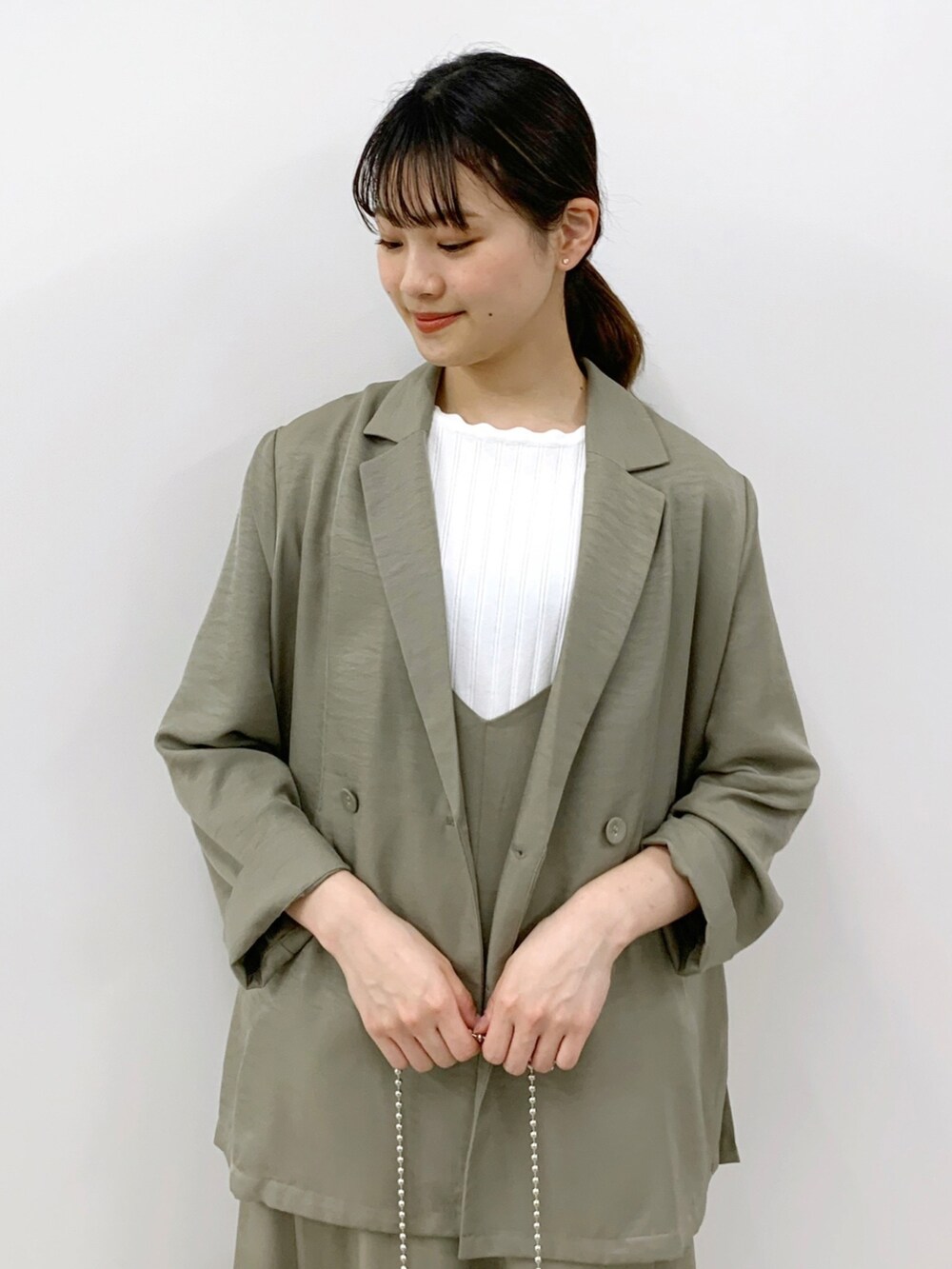 グリーン系のテーラードジャケット、グリーン系のワンピース、ホワイト系のニット/セーターを着用したレディースの春コーディネートの4枚目の写真