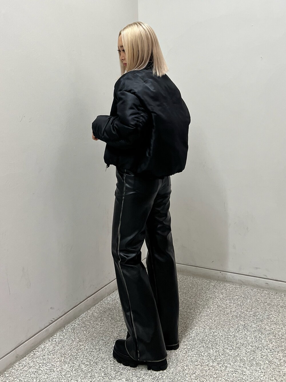 ブラック系のブルゾン、ホワイト系のニット/セーター、ブラック系のブーツを着用したレディースの秋コーディネートの2枚目の写真