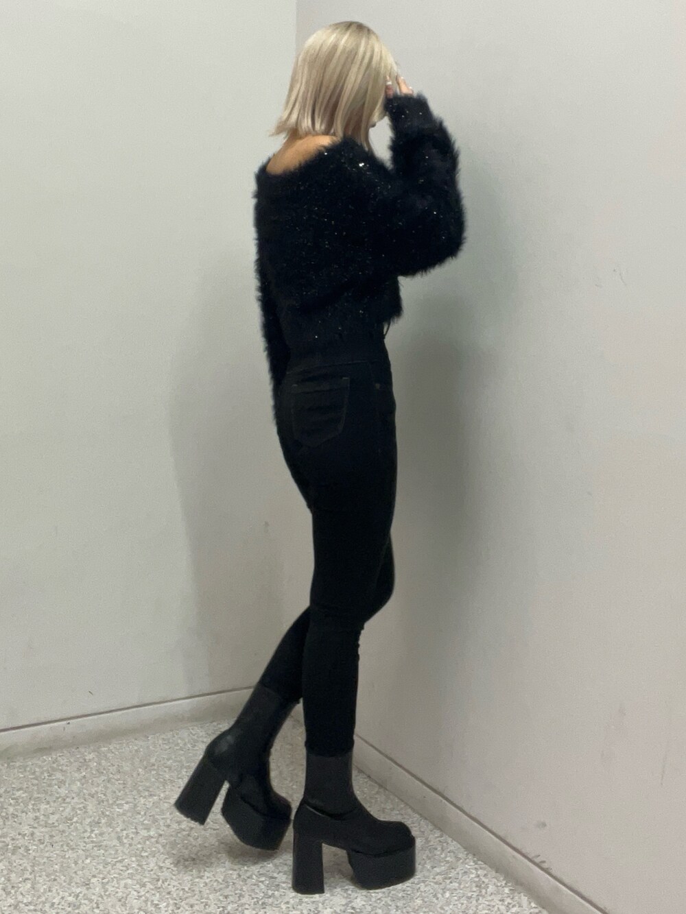 ブラック系のニット/セーター、ブラック系のデニムパンツ、ブラック系のブーツを着用したレディースの秋コーディネートの2枚目の写真