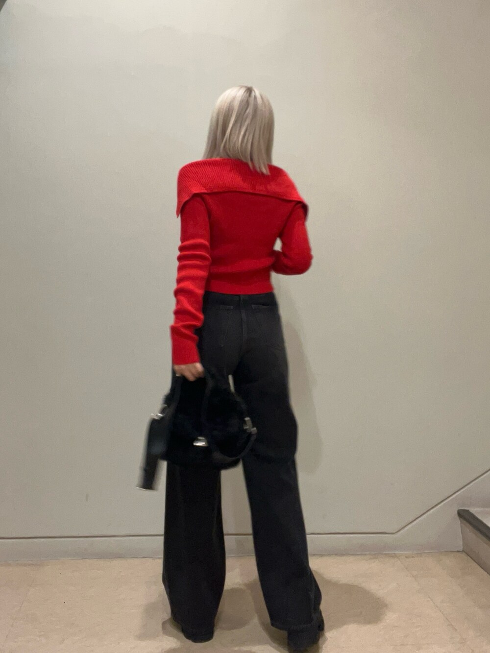 レッド系のニット/セーター、ブラック系のデニムパンツ、ブラック系のハンドバッグを着用したレディースの秋コーディネートの3枚目の写真