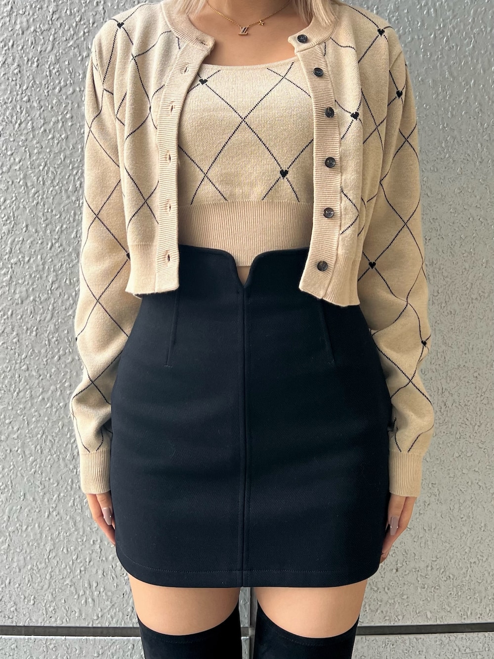 ブラック系のスカート、ベージュ系のニット/セーター、ブラック系のブーツを着用したレディースの秋コーディネートの4枚目の写真