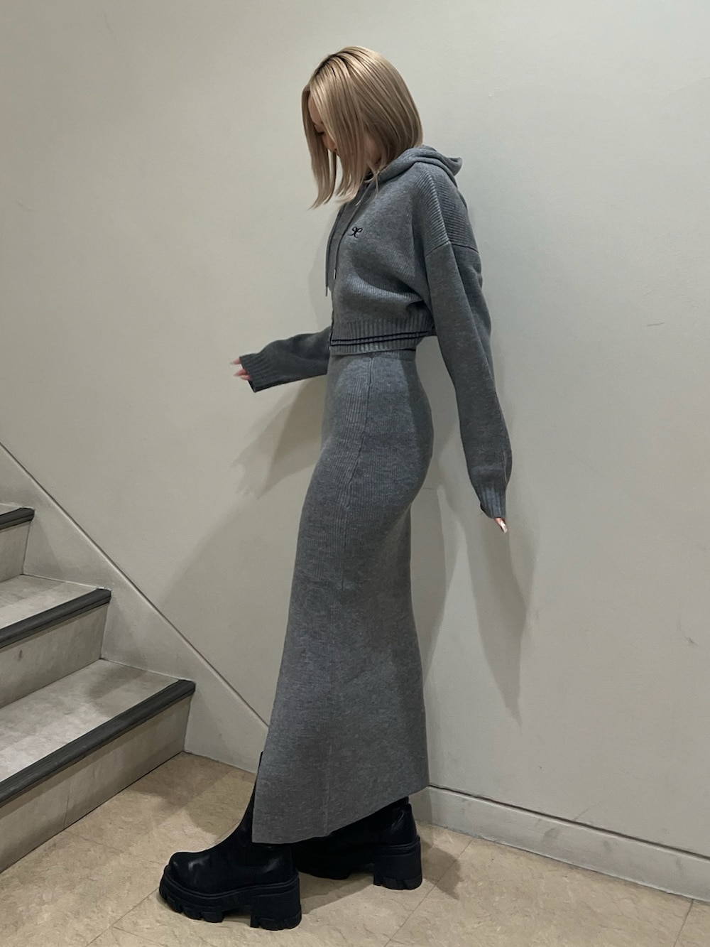 グレー系のニット/セーター、グレー系のスカート、ブラック系のブーツを着用したレディースの秋コーディネートの2枚目の写真