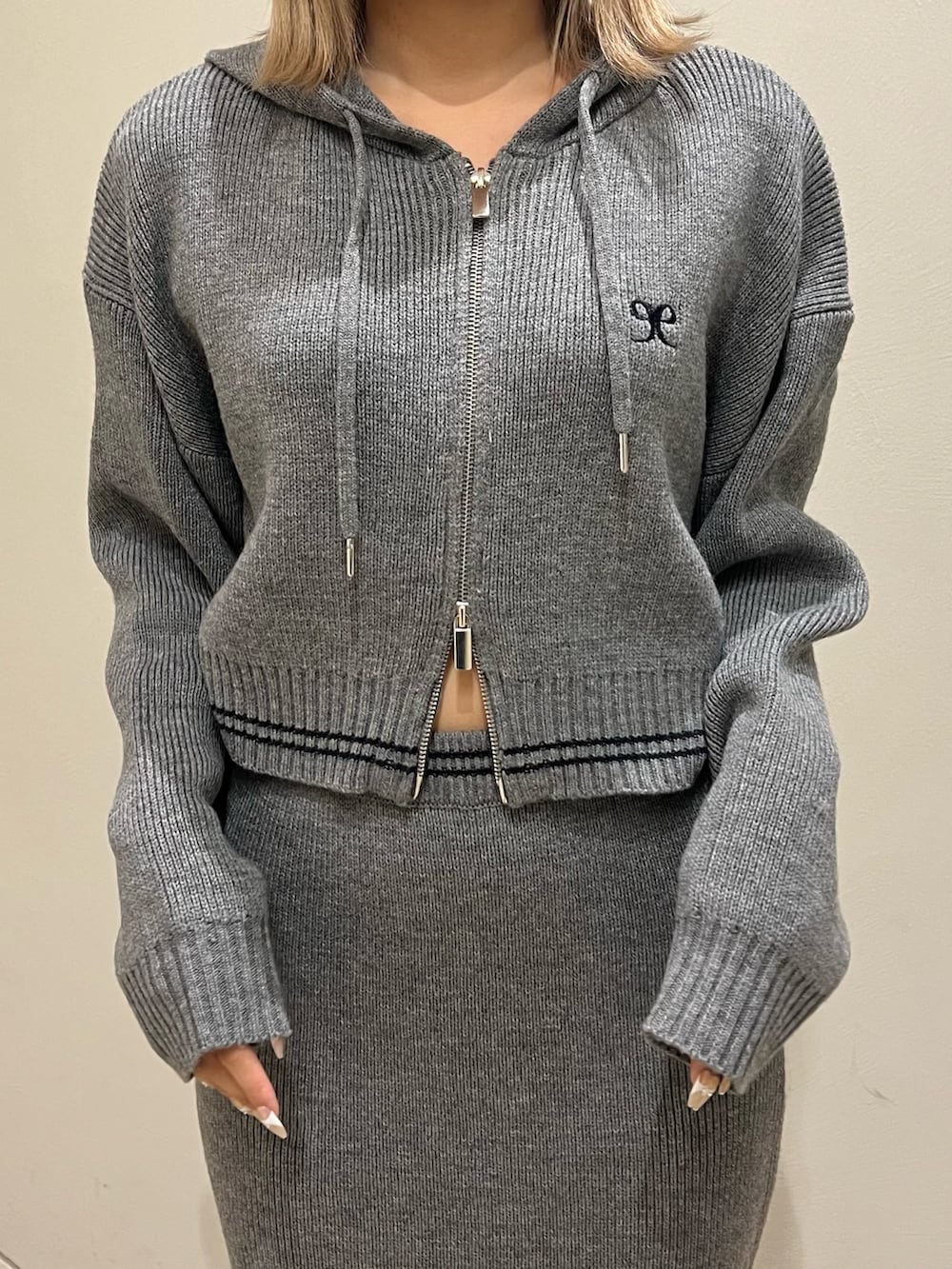 グレー系のニット/セーター、グレー系のスカート、ブラック系のブーツを着用したレディースの秋コーディネートの4枚目の写真