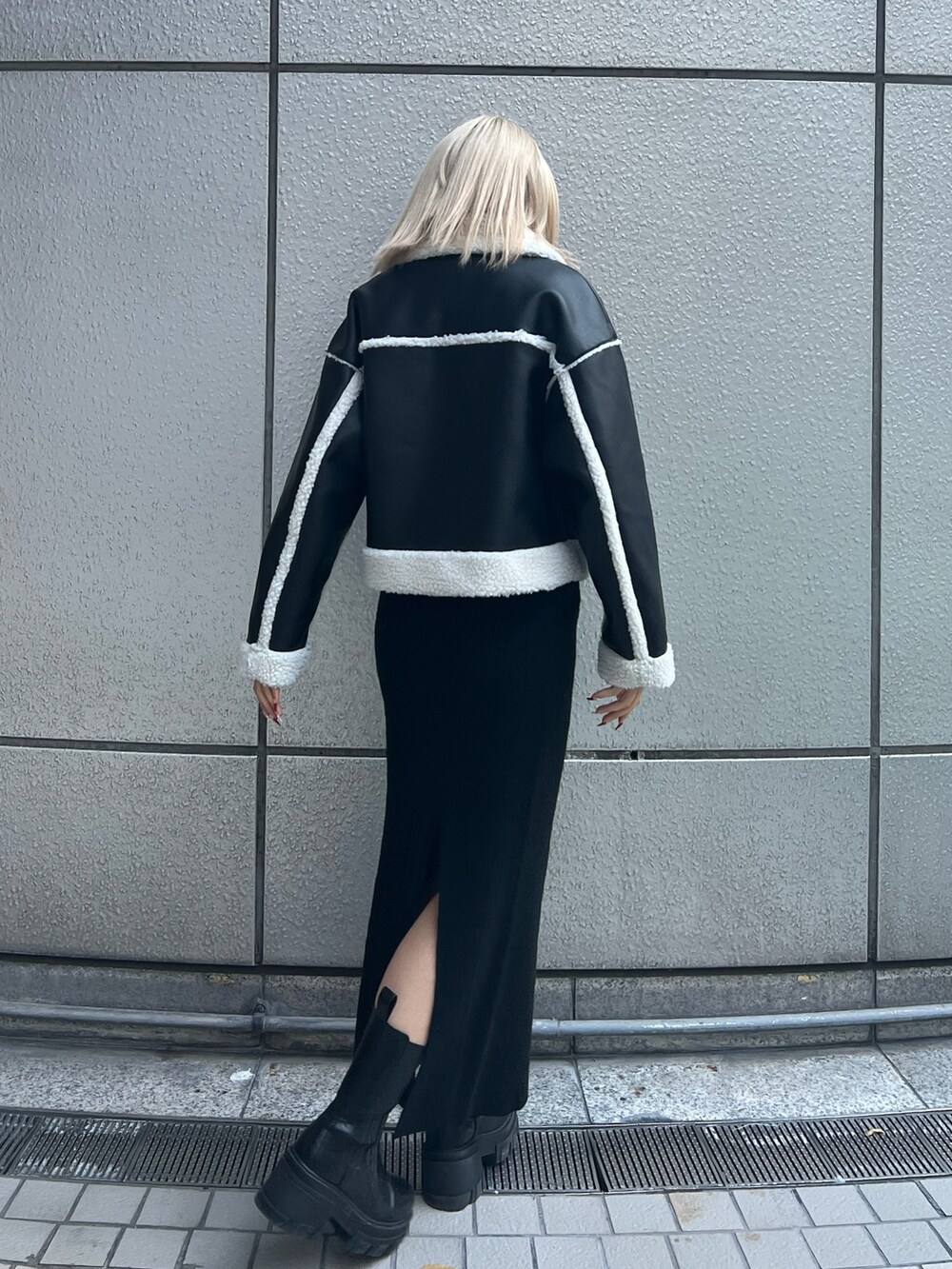 ブラック系のブルゾン、ブラック系のスカート、ブラック系のブーツを着用したレディースの冬コーディネートの3枚目の写真