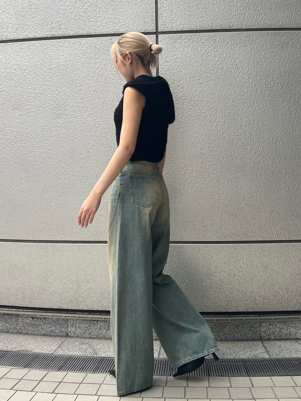 ブラック系のニット/セーター、ブルー系のデニムパンツ、ブラック系のパンプスを着用したレディースの春コーディネートの2枚目の写真