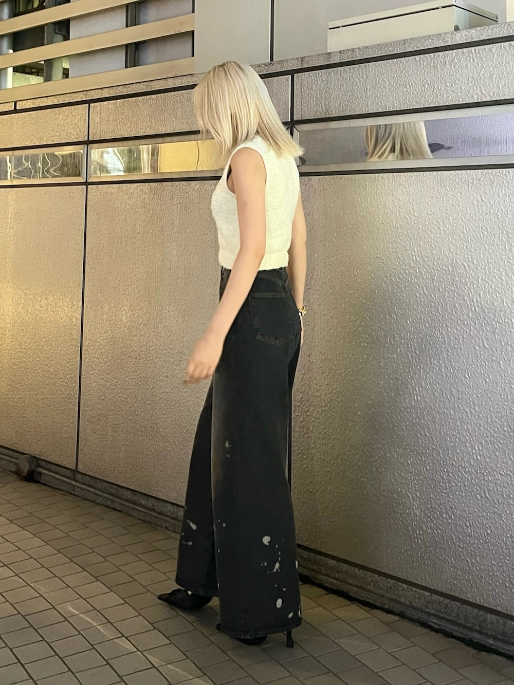 ホワイト系のニット/セーター、ブラック系のデニムパンツ、ブラック系のパンプスを着用したレディースの夏コーディネートの2枚目の写真