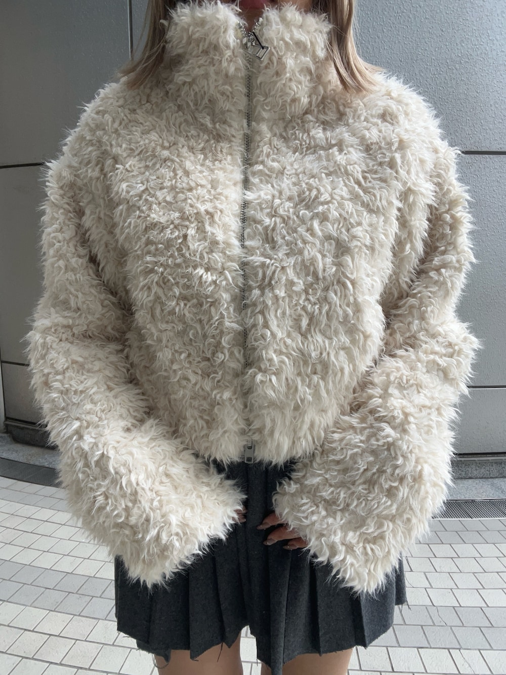 ホワイト系のブルゾン、グレー系のスカート、その他のブーツを着用したレディースの秋コーディネートの4枚目の写真