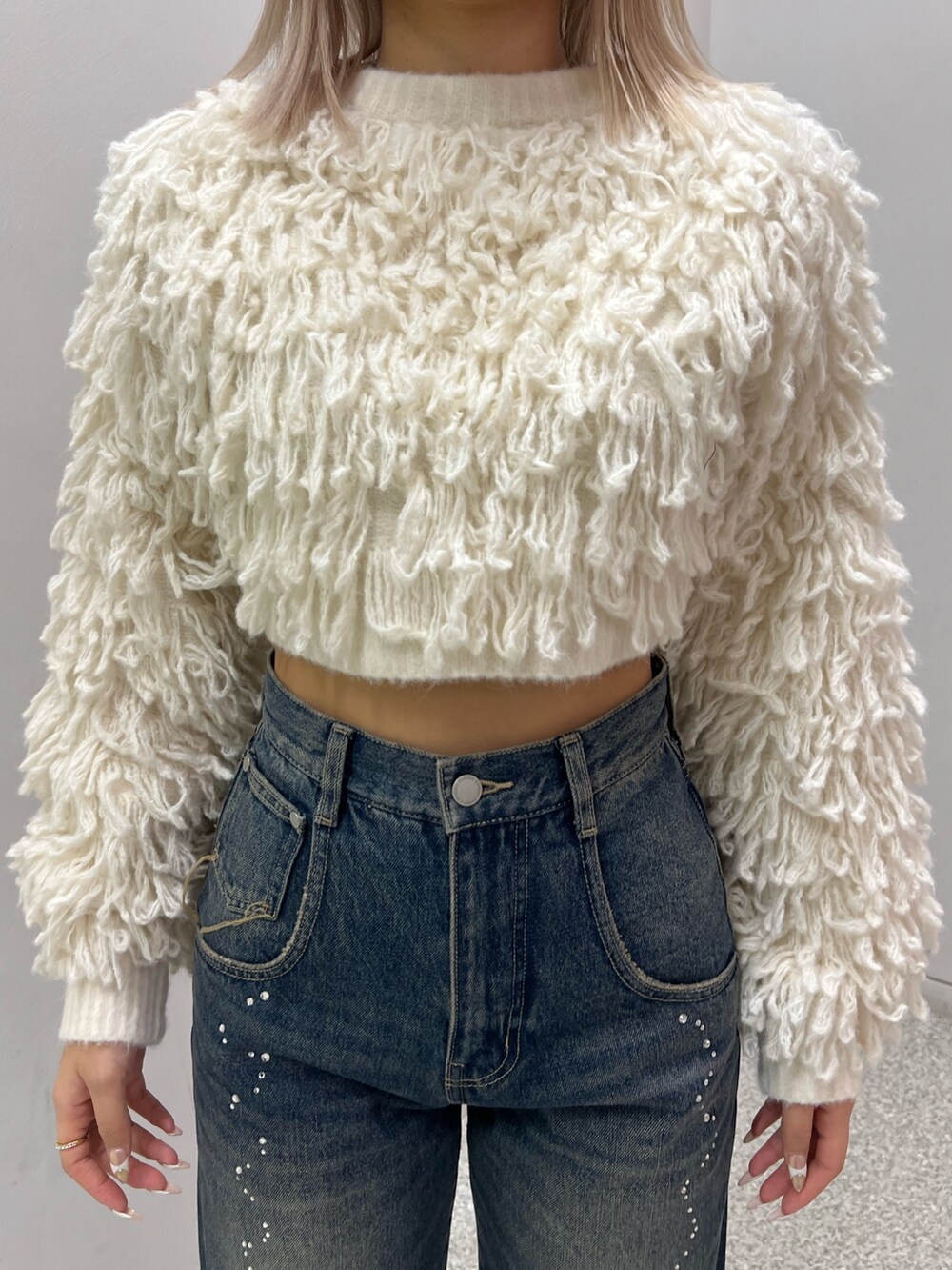 ブルー系のデニムパンツ、ブラック系のブーツ、ホワイト系のニット/セーターを着用したレディースの秋コーディネートの4枚目の写真