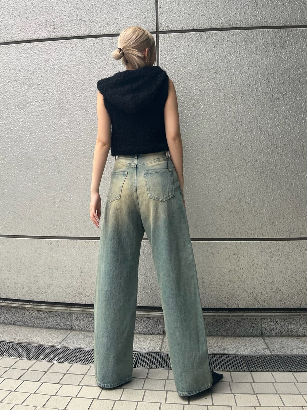 ブラック系のニット/セーター、ブルー系のデニムパンツ、ブラック系のパンプスを着用したレディースの春コーディネートの3枚目の写真