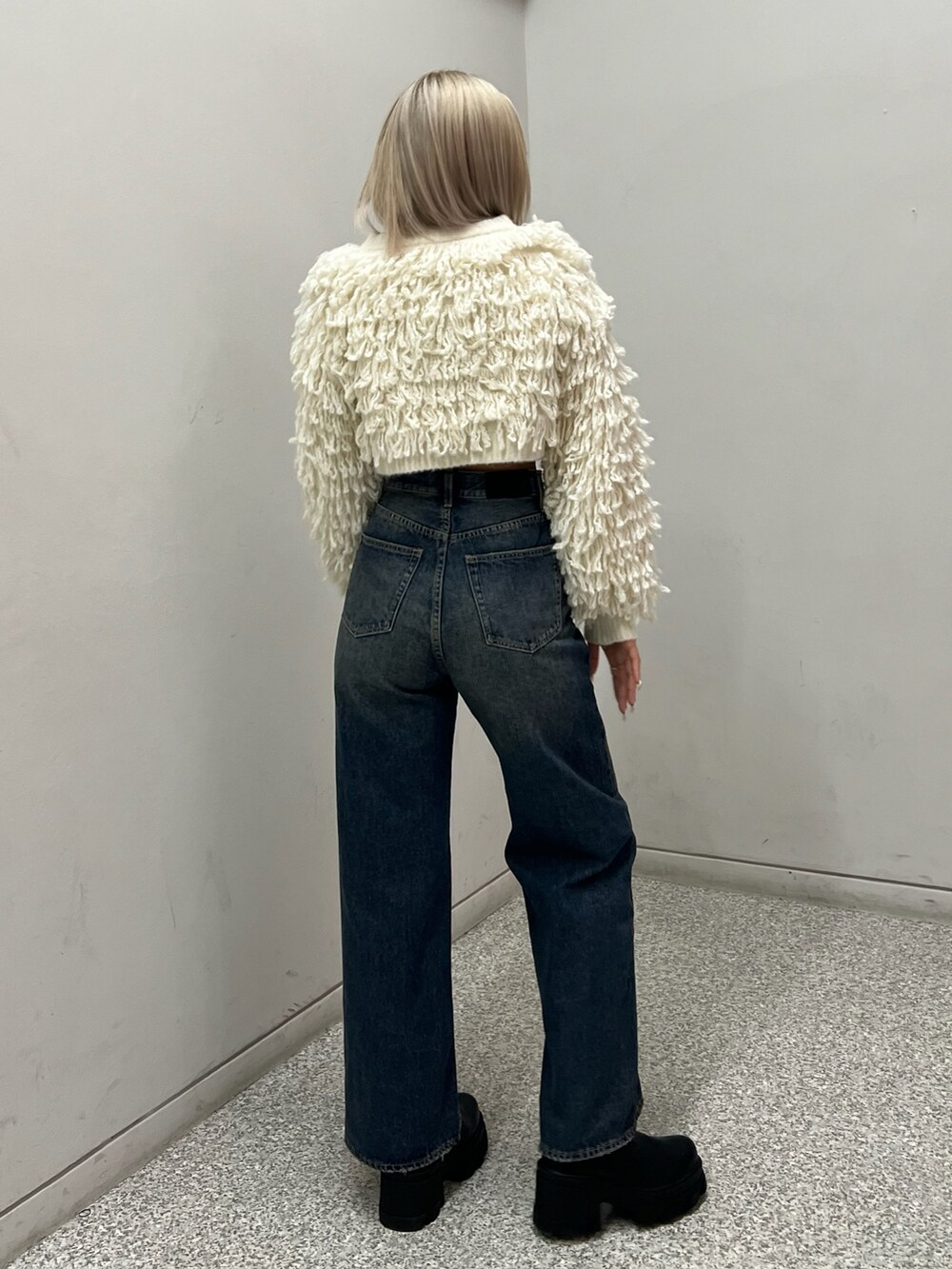 ブルー系のデニムパンツ、ブラック系のブーツ、ホワイト系のニット/セーターを着用したレディースの秋コーディネートの3枚目の写真