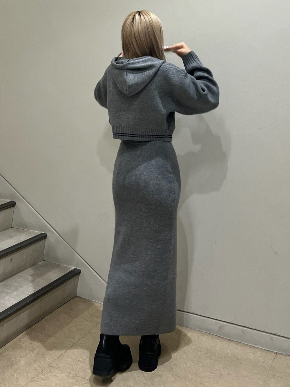 グレー系のニット/セーター、グレー系のスカート、ブラック系のブーツを着用したレディースの秋コーディネートの3枚目の写真