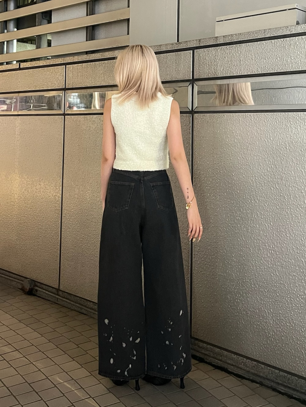 ホワイト系のニット/セーター、ブラック系のデニムパンツ、ブラック系のパンプスを着用したレディースの夏コーディネートの3枚目の写真