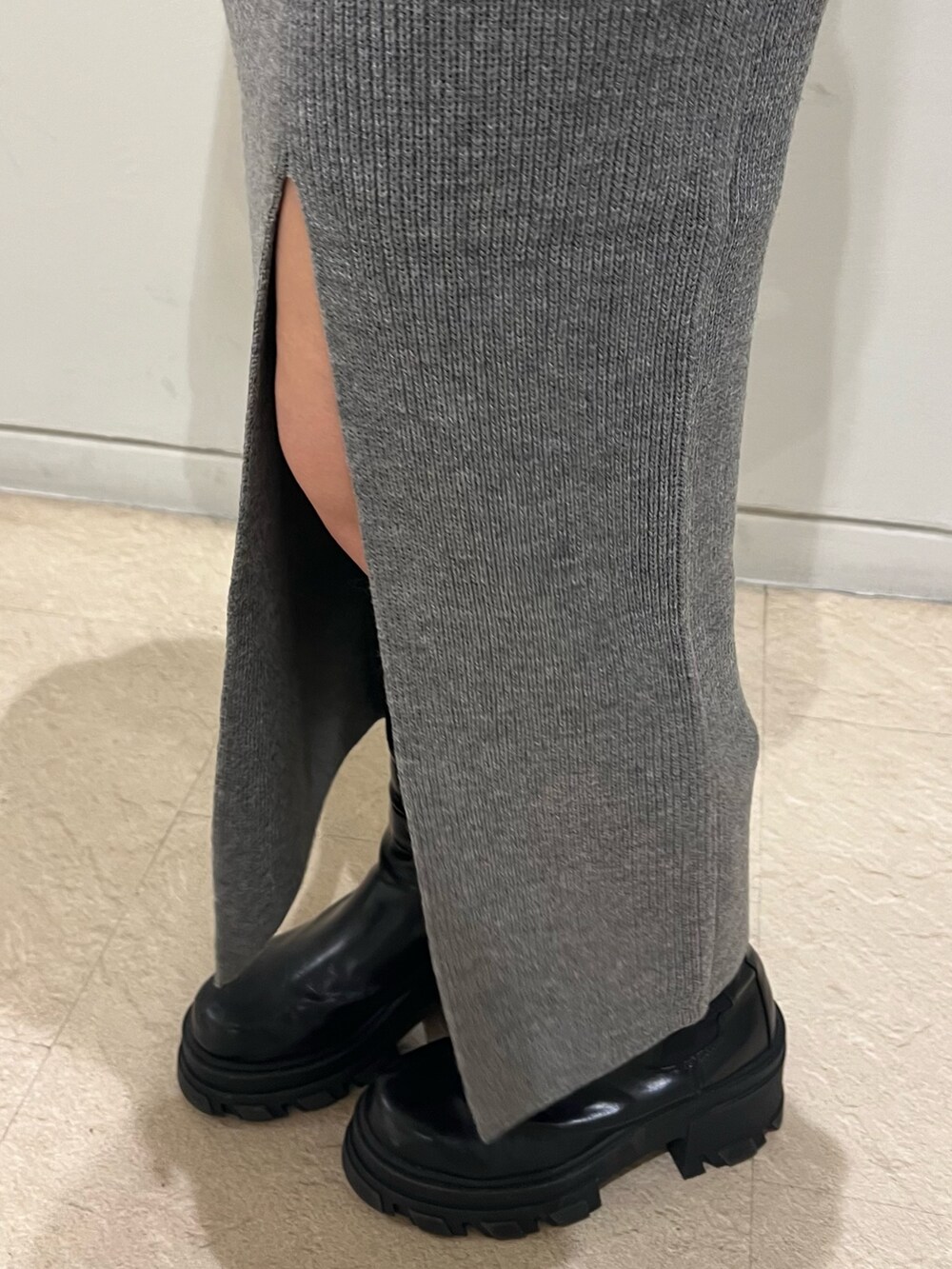 グレー系のニット/セーター、グレー系のスカート、ブラック系のブーツを着用したレディースの秋コーディネートの5枚目の写真