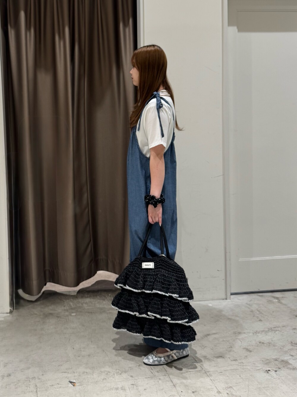 ブルー系のサロペット/オーバーオール、ブラック系のトートバッグ、ホワイト系のTシャツ/カットソーを着用したレディースの夏コーディネートの3枚目の写真