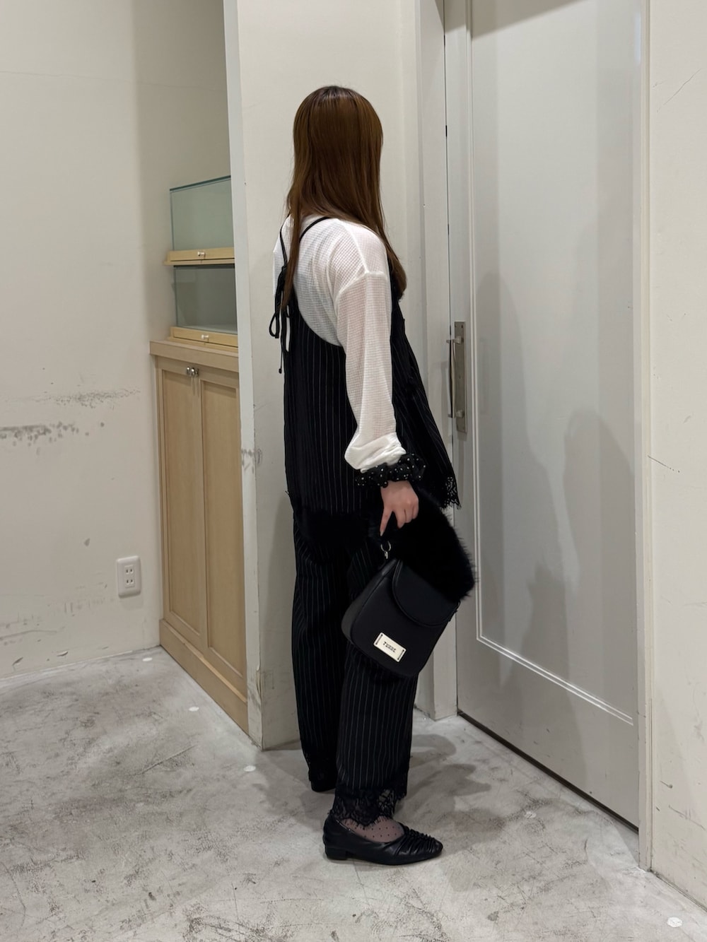 ブラック系のチュニック、ホワイト系のTシャツ/カットソー、ブラック系のショルダーバッグを着用したレディースの秋コーディネートの4枚目の写真