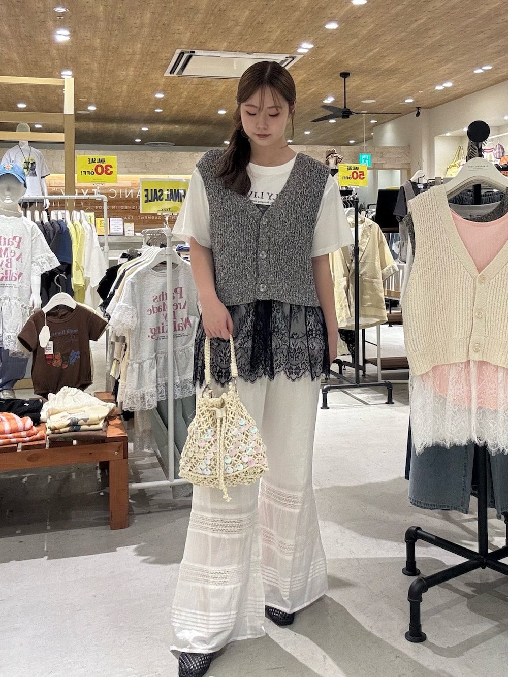 ブラック系のベスト、ホワイト系のショルダーバッグ、ホワイト系のTシャツ/カットソーを着用したレディースの夏コーディネートの2枚目の写真