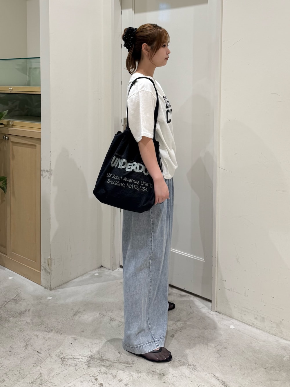 ブルー系のデニムパンツ、ホワイト系のTシャツ/カットソー、ブラック系のトートバッグを着用したレディースの夏コーディネートの4枚目の写真