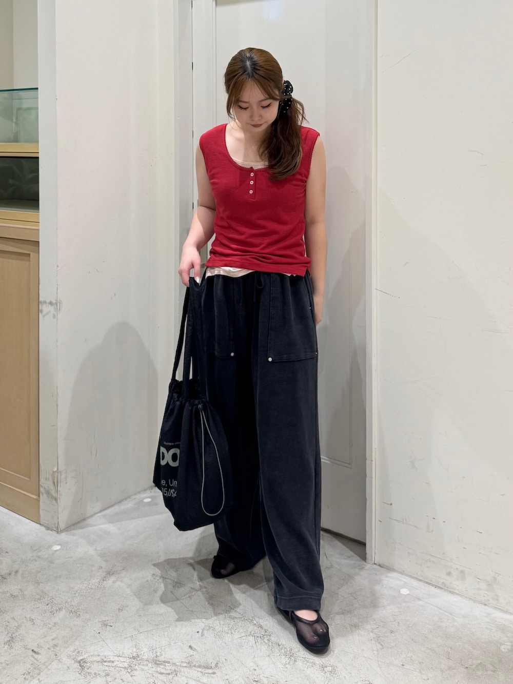 ブラック系のスウェットパンツ、レッド系のタンクトップ、ブラック系のトートバッグを着用したレディースの夏コーディネートの2枚目の写真