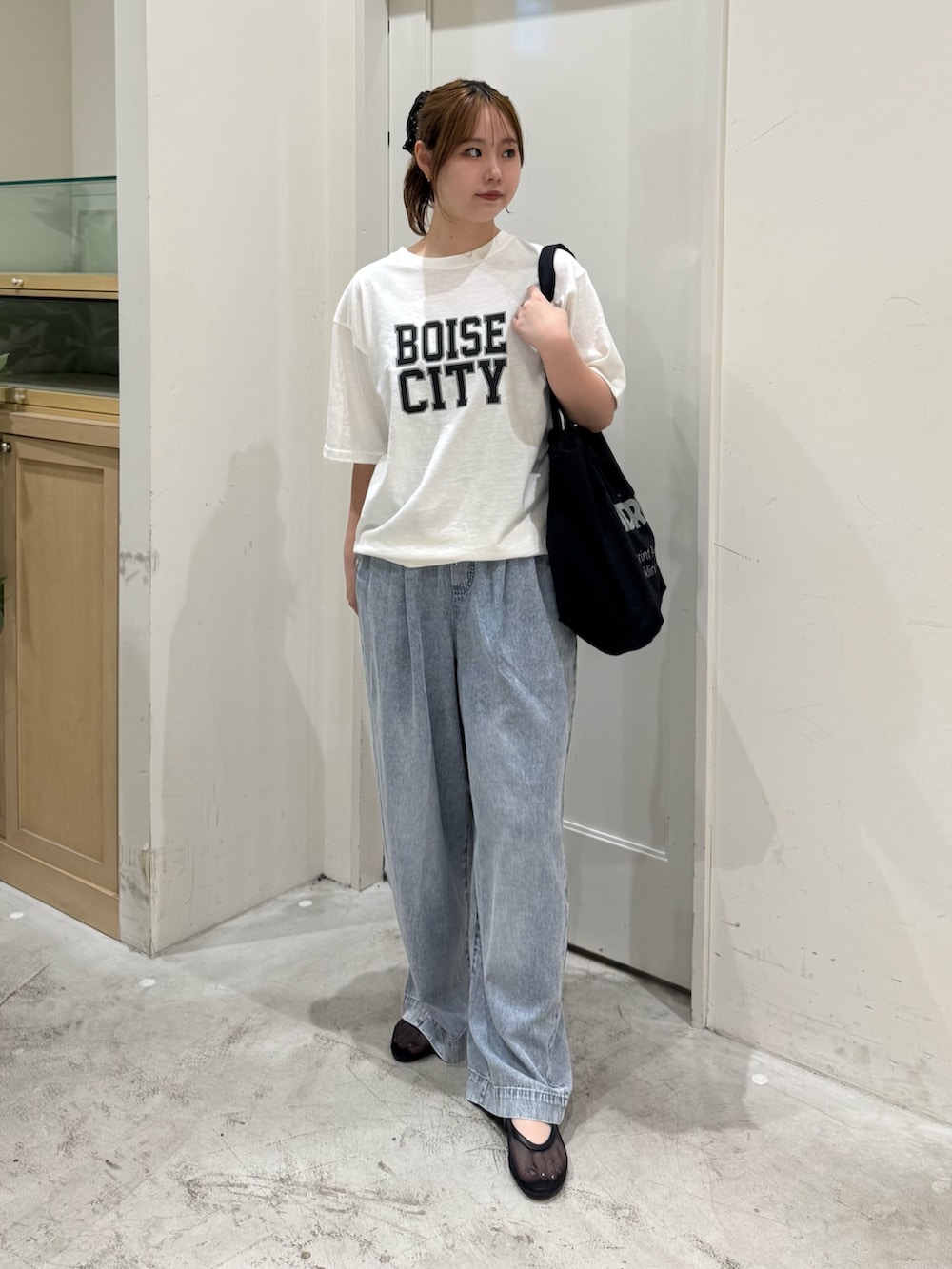 ブルー系のデニムパンツ、ホワイト系のTシャツ/カットソー、ブラック系のトートバッグを着用したレディースの夏コーディネートの2枚目の写真