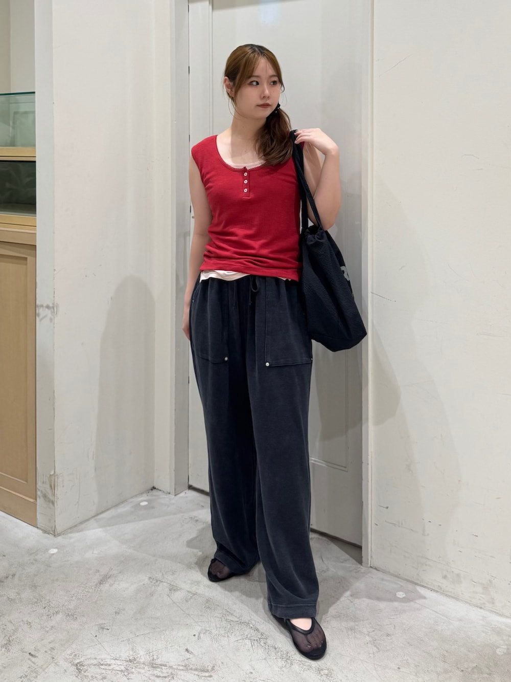 ブラック系のスウェットパンツ、レッド系のタンクトップ、ブラック系のトートバッグを着用したレディースの夏コーディネートの3枚目の写真