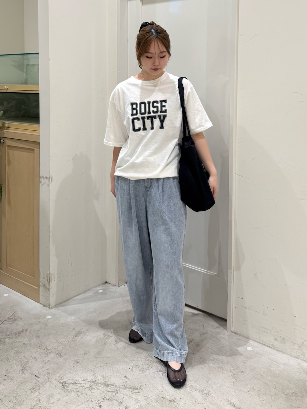 ブルー系のデニムパンツ、ホワイト系のTシャツ/カットソー、ブラック系のトートバッグを着用したレディースの夏コーディネートの3枚目の写真