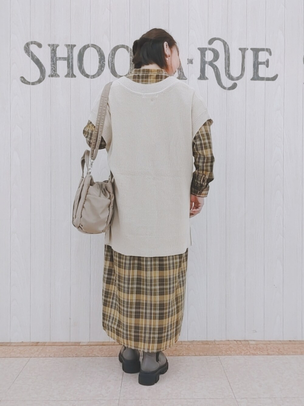 ベージュ系のベスト、ベージュ系のトートバッグ、イエロー系のワンピースを着用したレディースの秋コーディネートの3枚目の写真