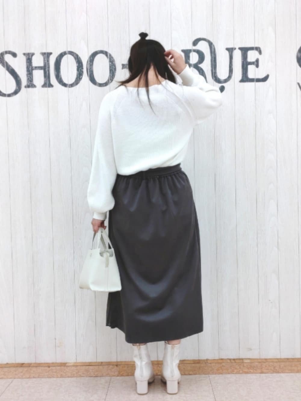 ホワイト系のトートバッグ、ホワイト系のニット/セーター、グレー系のスカートを着用したレディースの冬コーディネートの3枚目の写真