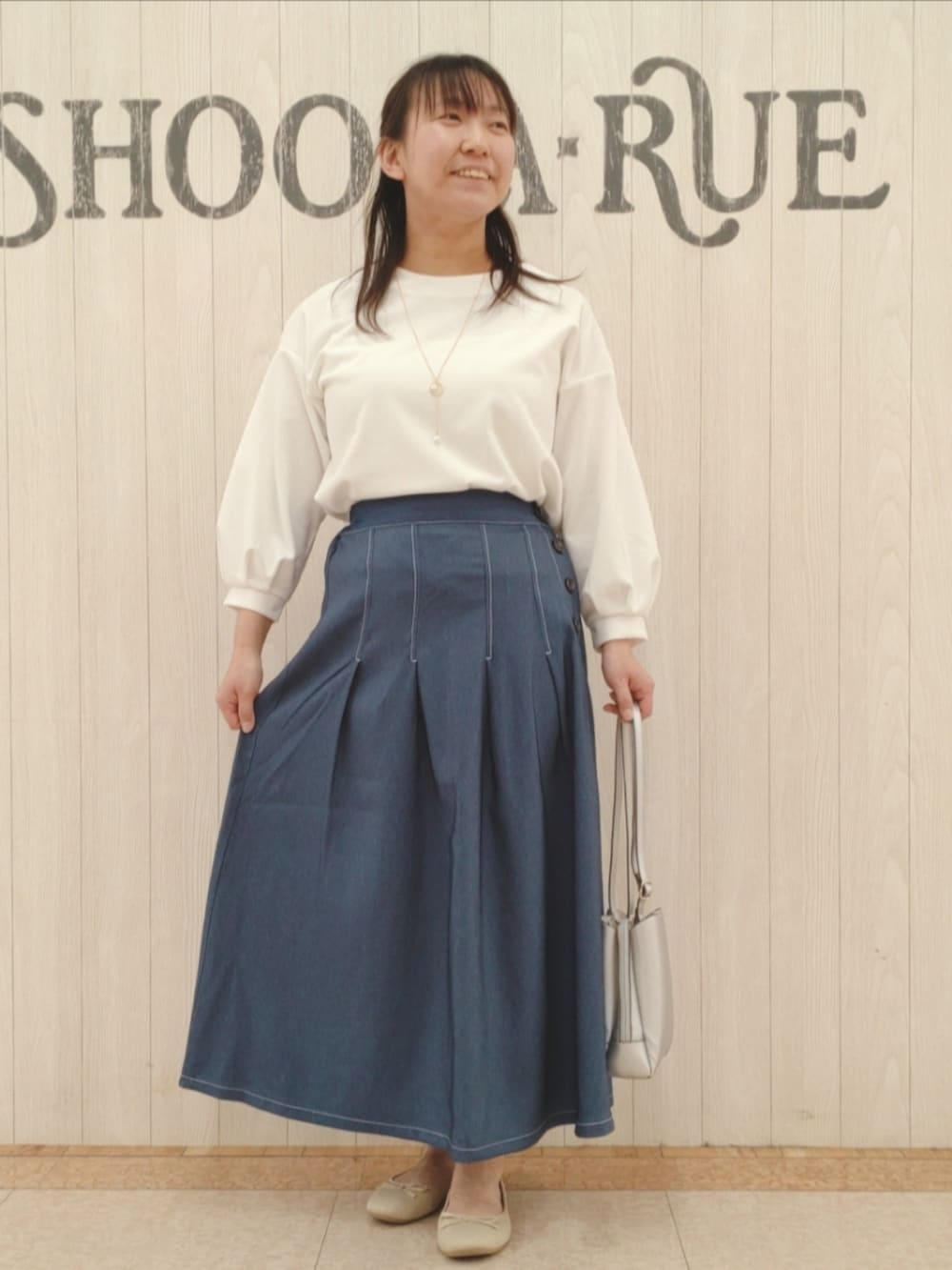 シルバー系のショルダーバッグ、ベージュ系のブルゾン、ホワイト系のTシャツ/カットソーを着用したレディースの春コーディネートの4枚目の写真