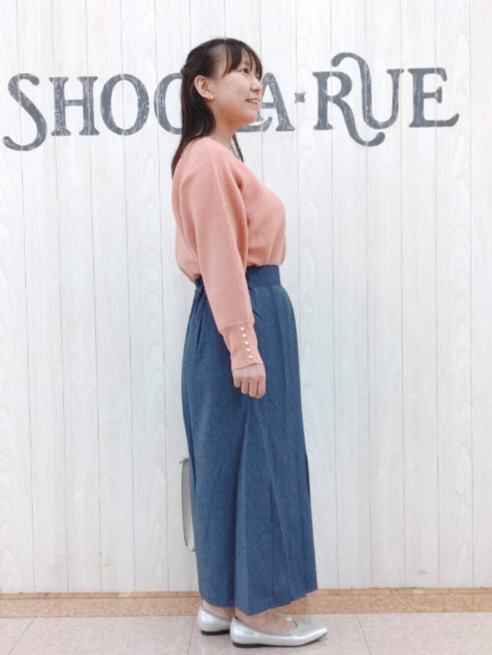 ピンク系のニット/セーター、ブルー系のスカート、グレー系のトートバッグを着用したレディースの秋コーディネートの2枚目の写真