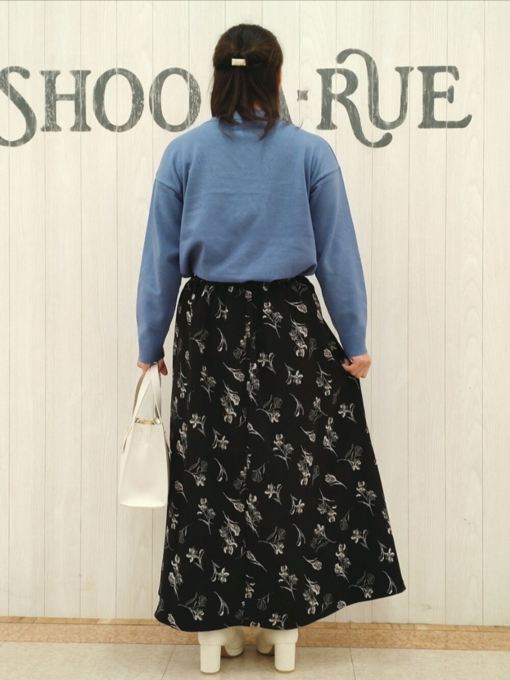 ブルー系のニット/セーター、ホワイト系のトートバッグ、ブラック系のスカートを着用したレディースの秋コーディネートの3枚目の写真