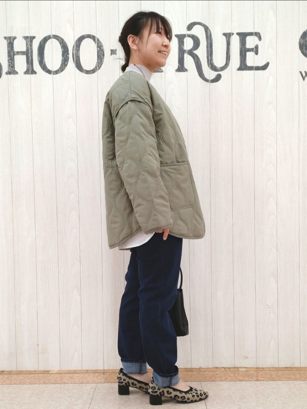 グレー系のニット/セーター、グリーン系のその他アウター、ブラック系のショルダーバッグを着用したレディースの春コーディネートの2枚目の写真