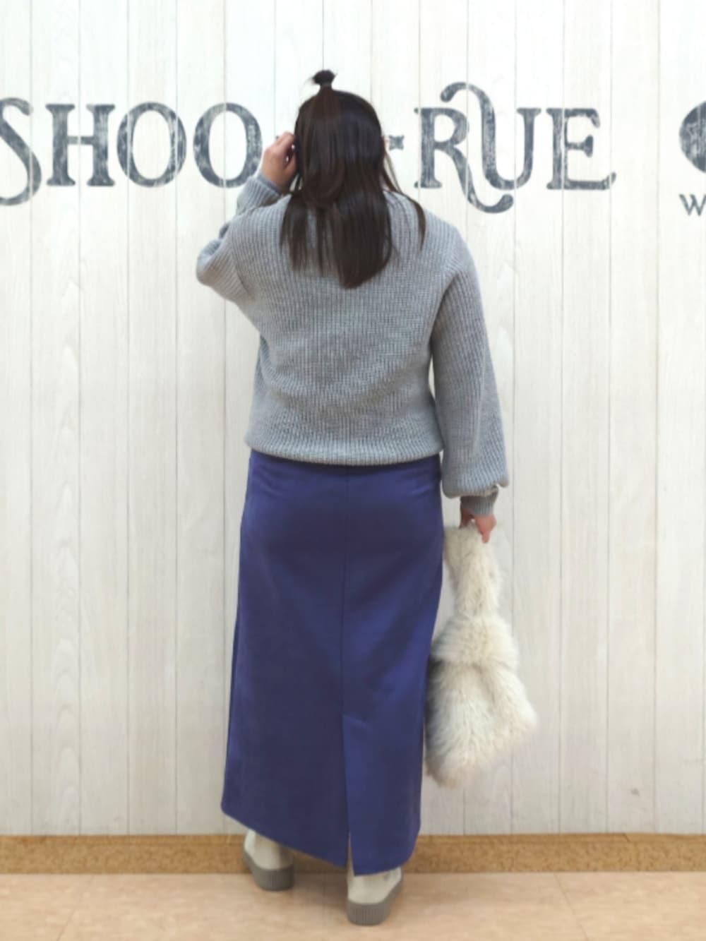 グレー系のニット/セーター、ブルー系のスカート、ホワイト系のトートバッグを着用したレディースの春コーディネートの3枚目の写真