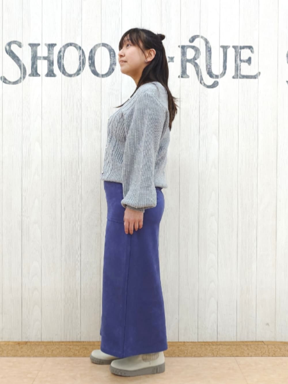 グレー系のニット/セーター、ブルー系のスカート、ホワイト系のトートバッグを着用したレディースの春コーディネートの2枚目の写真