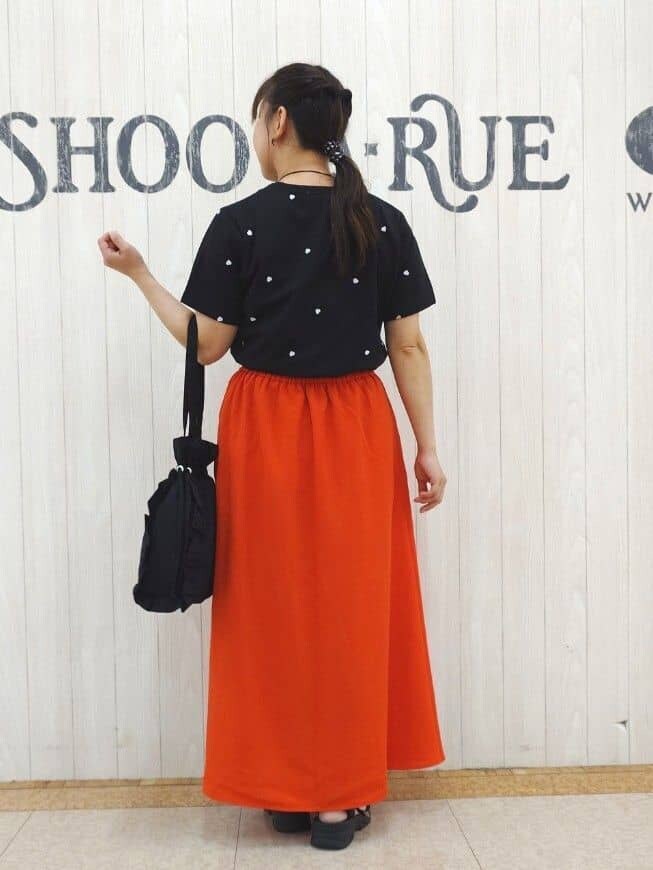 ブラック系のTシャツ/カットソー、レッド系のスカート、ブラック系のサンダルを着用したレディースの夏コーディネートの3枚目の写真