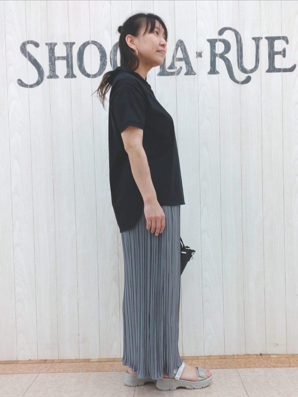 ブラック系のTシャツ/カットソー、ブラック系のトートバッグ、グレー系のスカートを着用したレディースの夏コーディネートの2枚目の写真