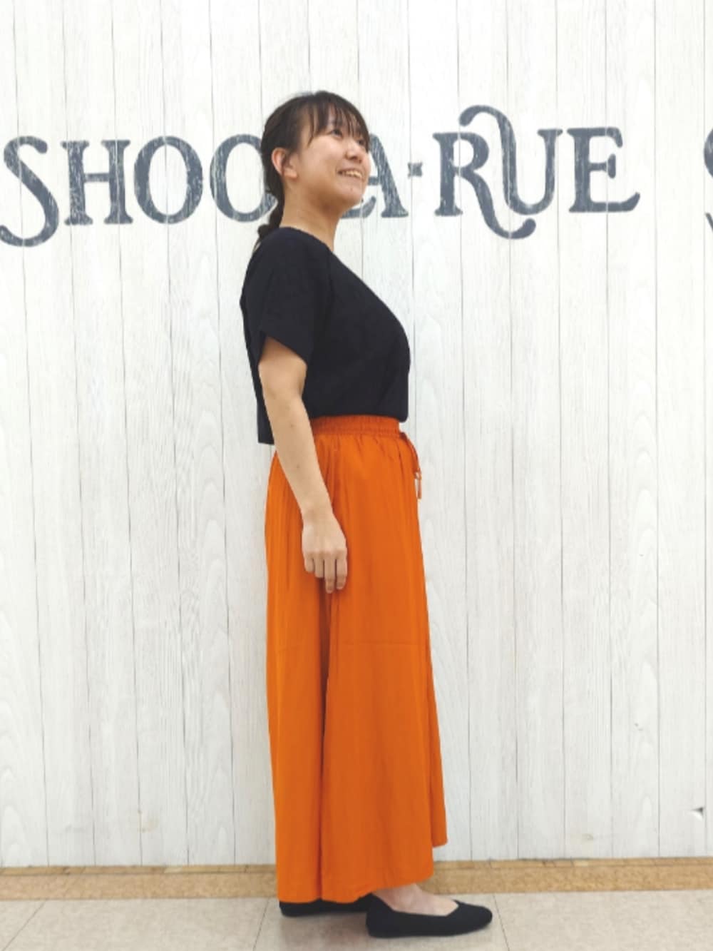 ブラック系のTシャツ/カットソー、オレンジ系のその他パンツ、ブラック系のトートバッグを着用したレディースの秋コーディネートの2枚目の写真