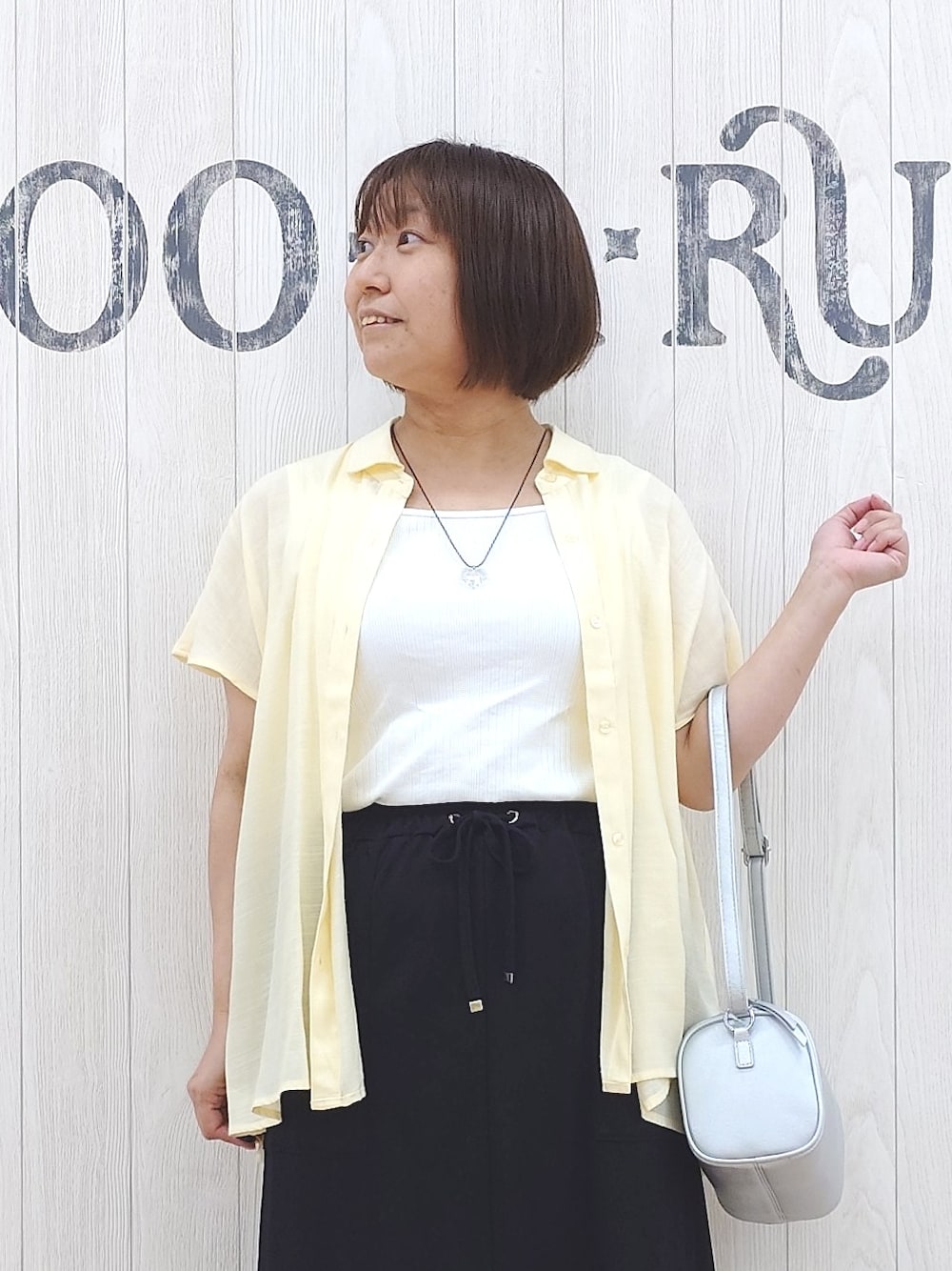 イエロー系のシャツ/ブラウス、ホワイト系のタンクトップ、ブラック系のスカートを着用したレディースの夏コーディネートの5枚目の写真