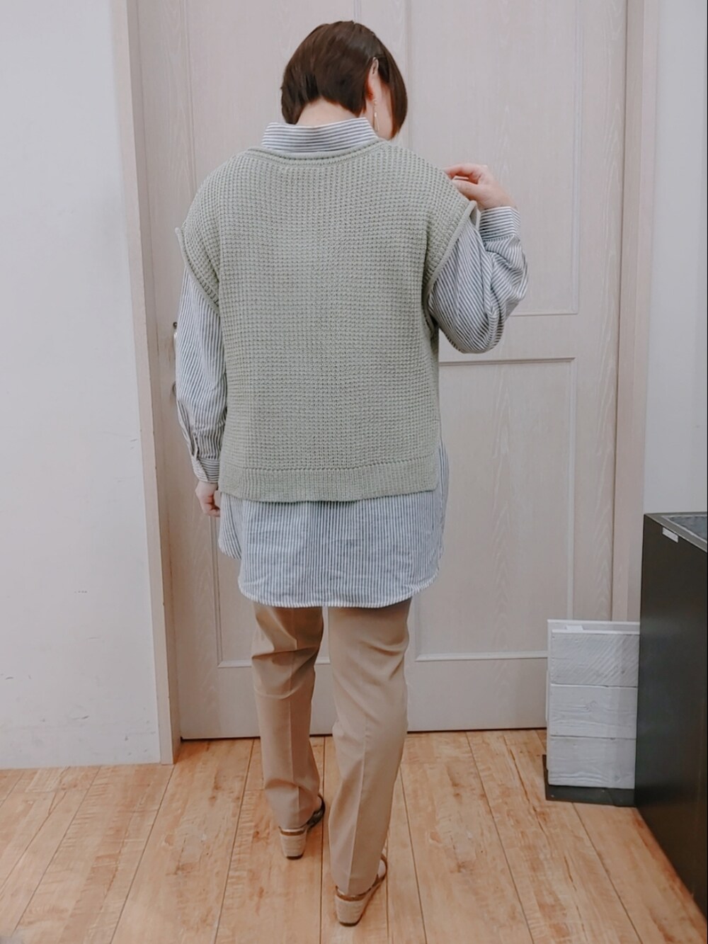 グリーン系のベスト、ブラック系のシャツ/ブラウス、ブラウン系のハンドバッグを着用したレディースの春コーディネートの3枚目の写真