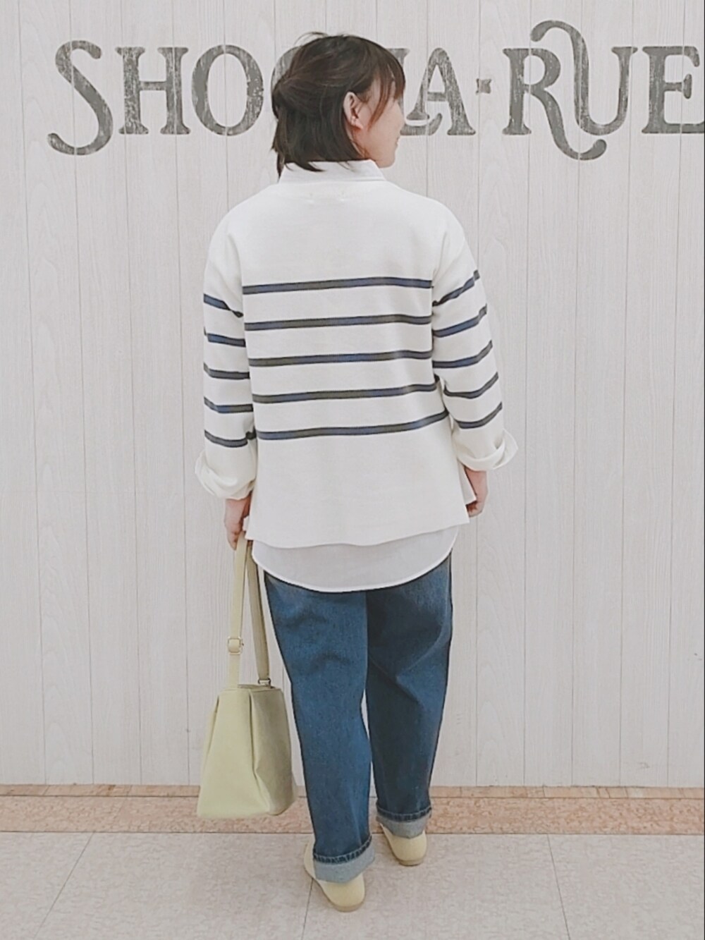 ブルー系のニット/セーター、ホワイト系のシャツ/ブラウス、イエロー系のショルダーバッグを着用したレディースの冬コーディネートの3枚目の写真