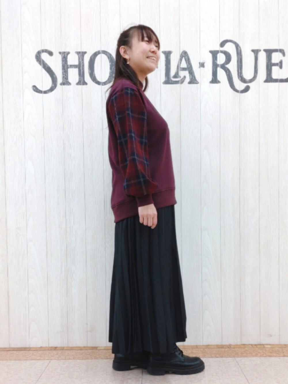 レッド系のスウェット、ブラック系のスカート、ブラック系のショルダーバッグを着用したレディースの冬コーディネートの2枚目の写真