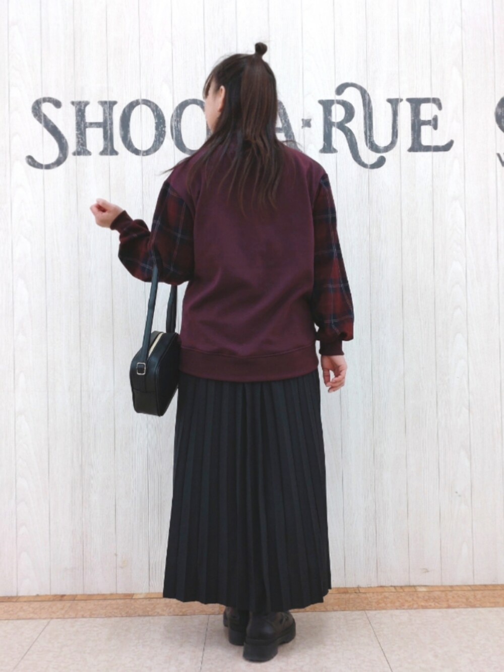 レッド系のスウェット、ブラック系のスカート、ブラック系のショルダーバッグを着用したレディースの冬コーディネートの3枚目の写真
