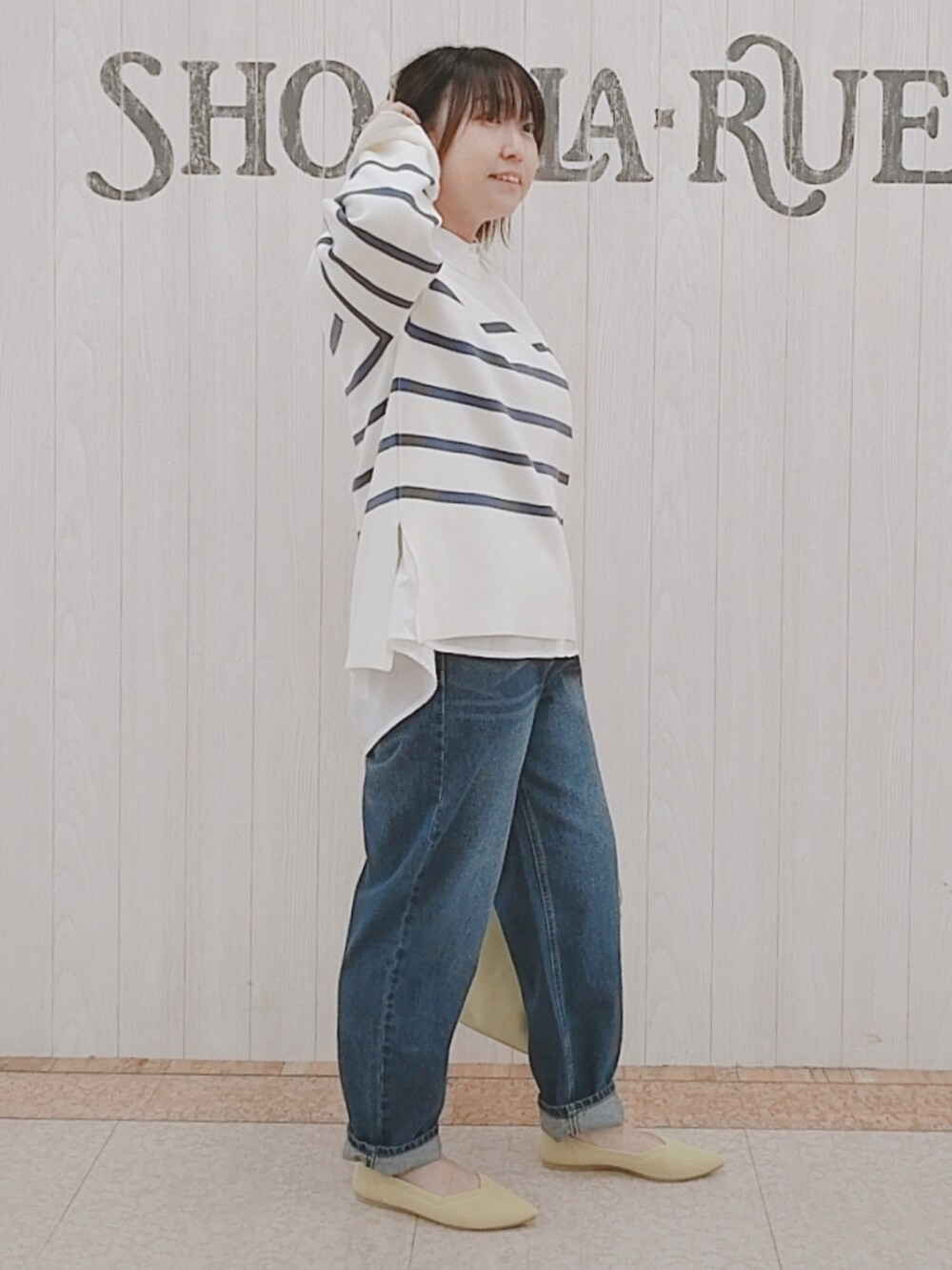 ブルー系のニット/セーター、ホワイト系のシャツ/ブラウス、イエロー系のショルダーバッグを着用したレディースの冬コーディネートの2枚目の写真