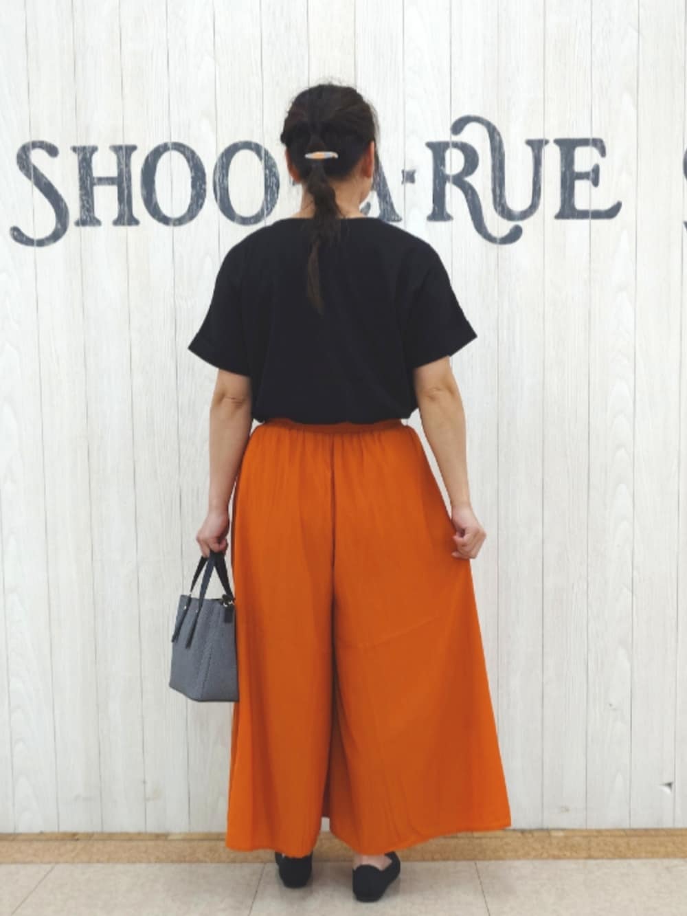 ブラック系のTシャツ/カットソー、オレンジ系のその他パンツ、ブラック系のトートバッグを着用したレディースの秋コーディネートの3枚目の写真