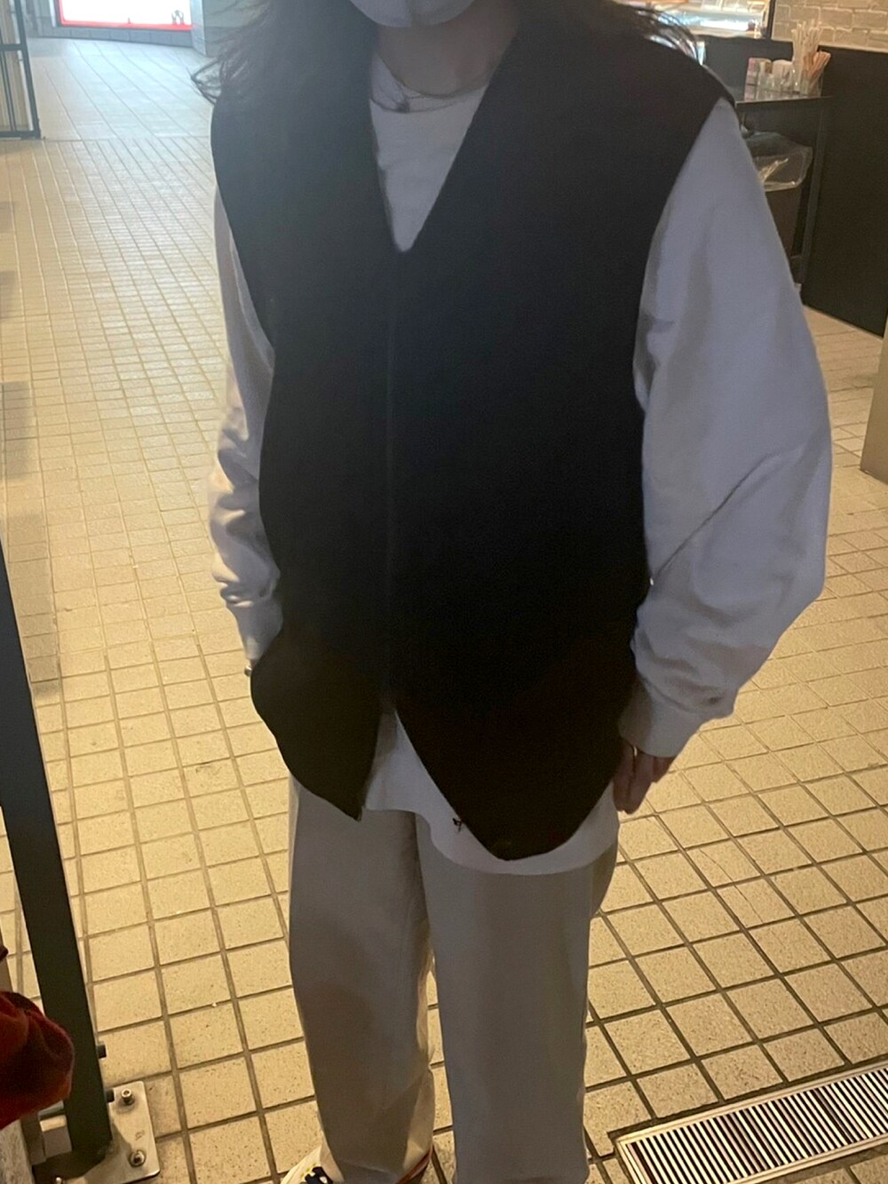 ベージュ系のパンツ、ホワイト系のスニーカー、ブラック系のベストを着用したレディースの冬コーディネートの2枚目の写真