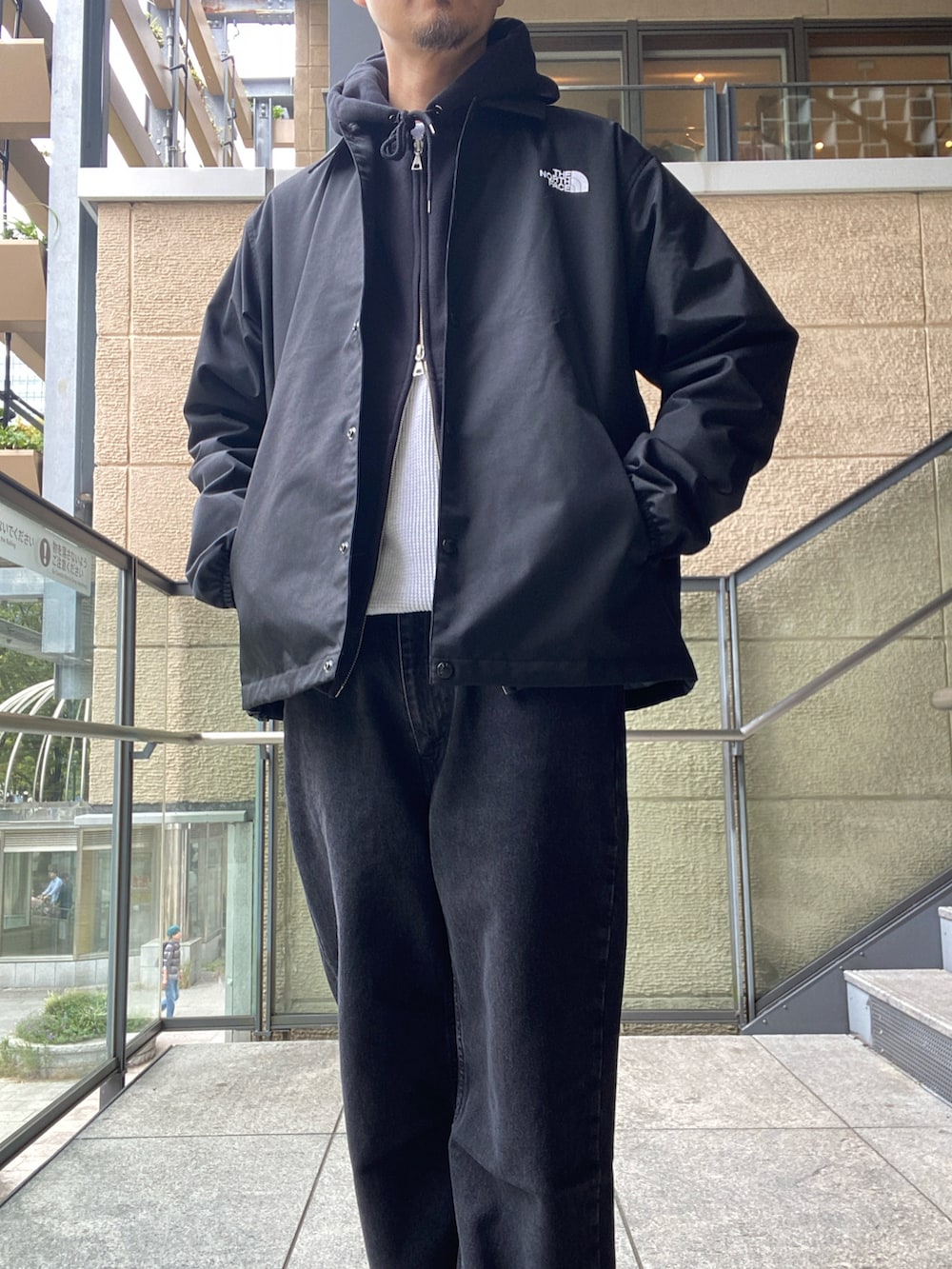 ブラック系のナイロンジャケット、ホワイト系のTシャツ/カットソー、ブラック系のデニムパンツを着用したメンズの秋コーディネートの6枚目の写真