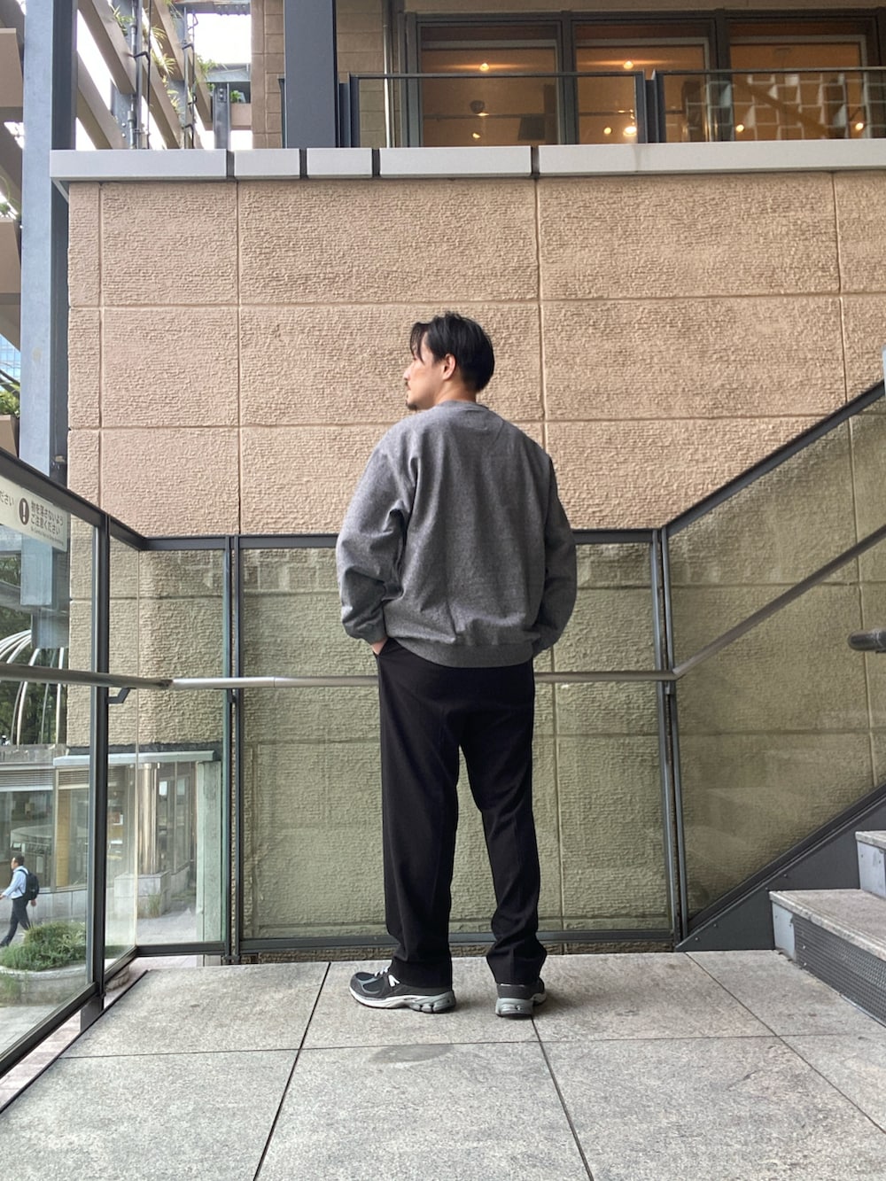 グレー系のスウェット、ブラック系のスラックス、ブラック系のスニーカーを着用したメンズの秋コーディネートの3枚目の写真