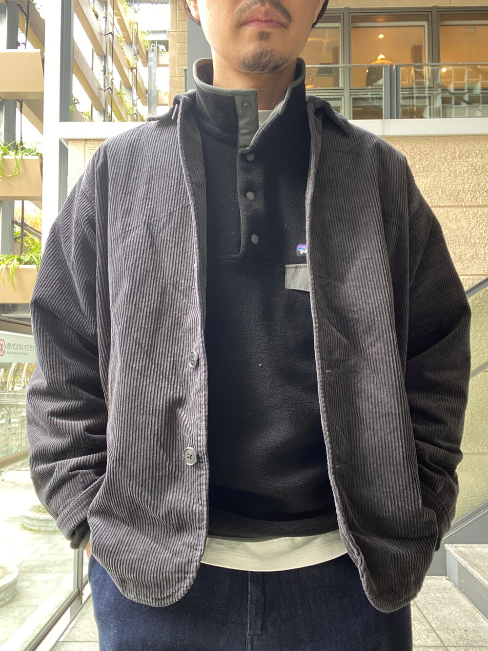 グレー系のカバーオール、ブラック系のトップス、ブルー系のデニムパンツを着用したメンズの秋コーディネートの3枚目の写真