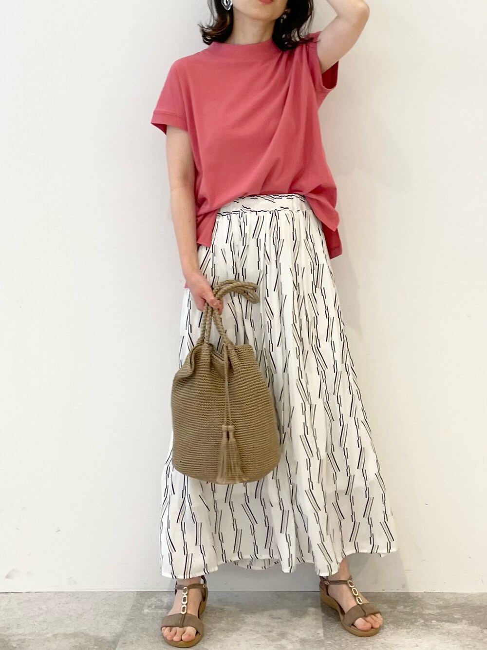 ホワイト系のスカート、ピンク系のTシャツ/カットソー、ベージュ系のサンダルを着用したレディースの春コーディネートの3枚目の写真